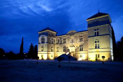 Terrasse en pierre spacieuse devant un bâtiment ancien en pierre sous un ciel bleu dégagé.