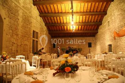 Terrasse en pierre spacieuse devant un bâtiment ancien en pierre sous un ciel bleu dégagé.