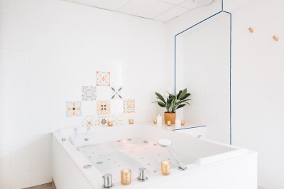 Terrain multisport extérieur avec panier de basket, filet de volley et clôture, entouré de végétation sous un ciel dégagé.