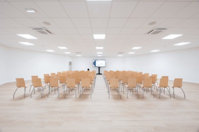 Terrain multisport extérieur avec panier de basket, filet de volley et clôture, entouré de végétation sous un ciel dégagé.