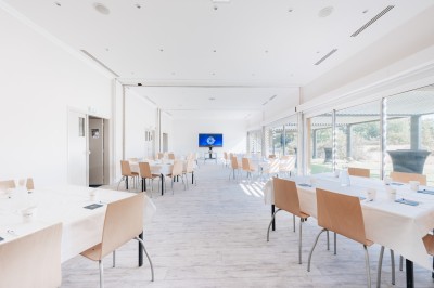 Terrain multisport extérieur avec panier de basket, filet de volley et clôture, entouré de végétation sous un ciel dégagé.