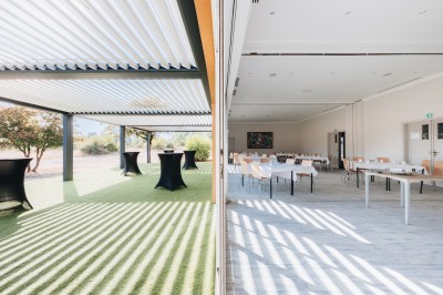 Terrain multisport extérieur avec panier de basket, filet de volley et clôture, entouré de végétation sous un ciel dégagé.