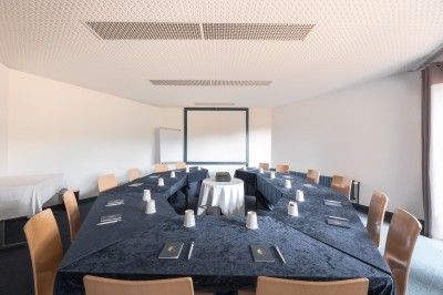 Terrain multisport extérieur avec panier de basket, filet de volley et clôture, entouré de végétation sous un ciel dégagé.