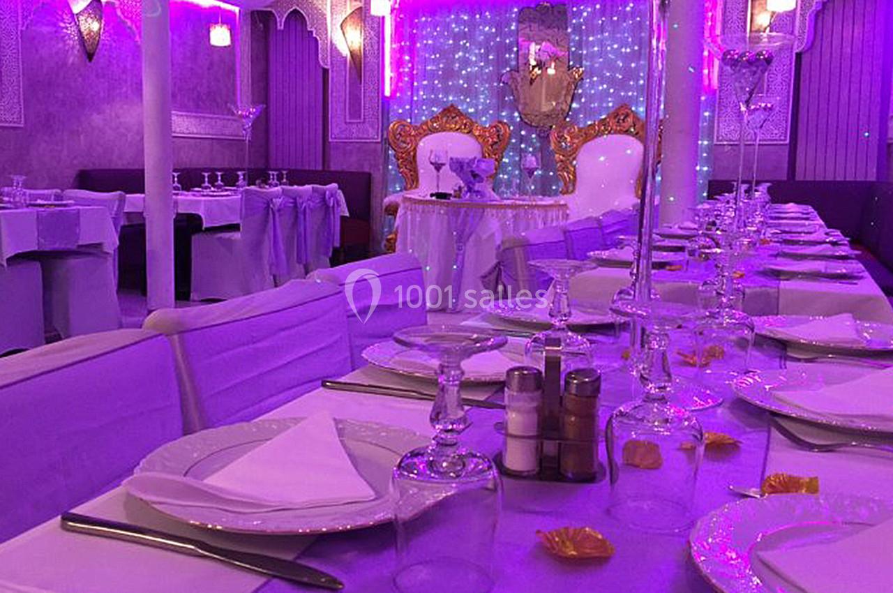Salle de réception décorée avec des tons violets, tables dressées avec vaisselle élégante et chaises couvertes.