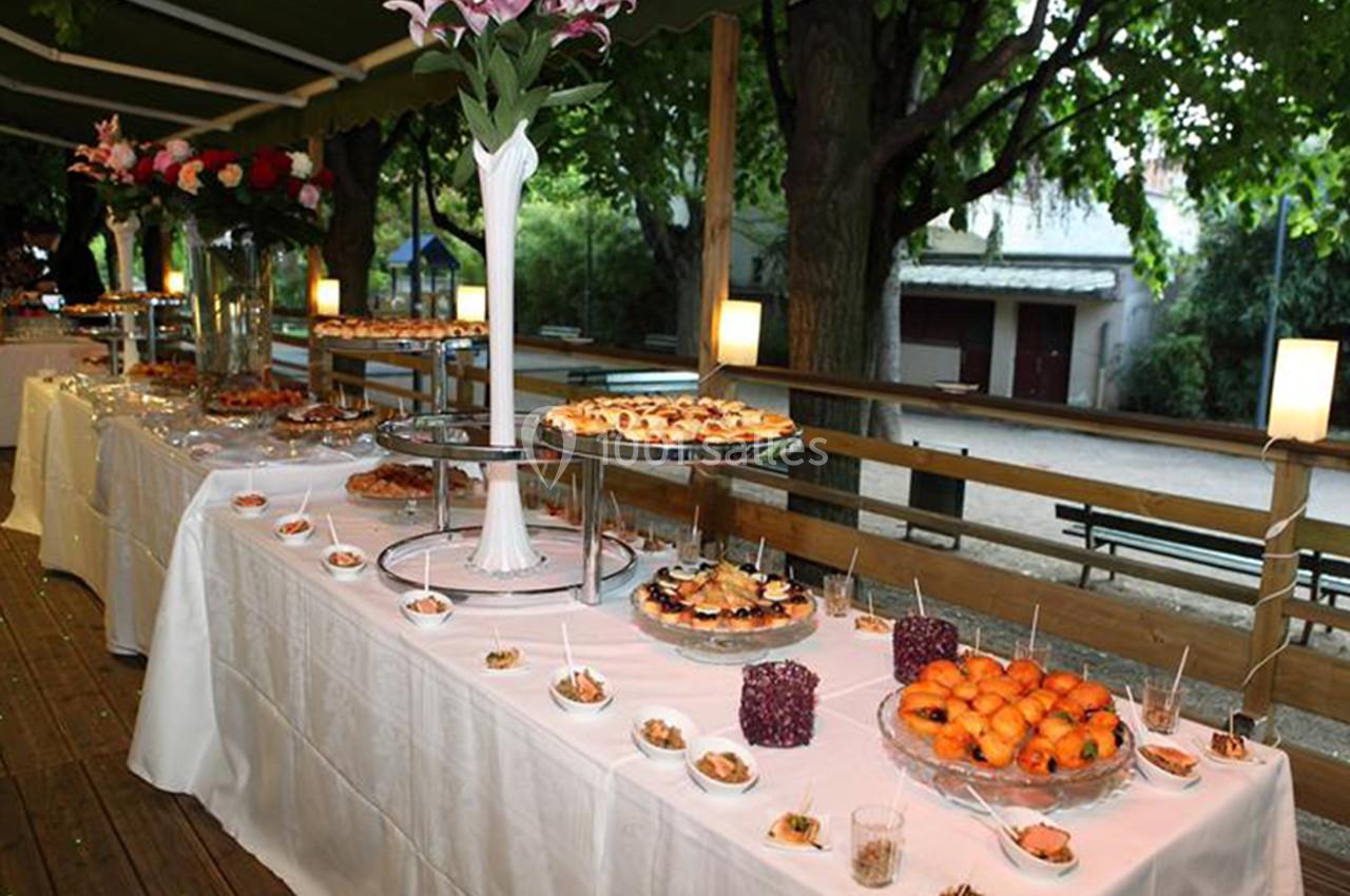 Buffet en extérieur avec une variété de plats et desserts disposés sur des tables décorées sous un auvent.