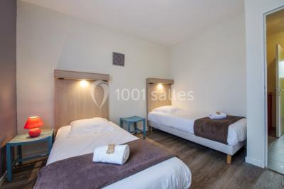 Salle de réunion lumineuse avec tables en U, chaises noires, grandes fenêtres donnant sur un jardin verdoyant.