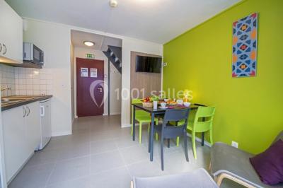 Salle de réunion lumineuse avec tables en U, chaises noires, grandes fenêtres donnant sur un jardin verdoyant.