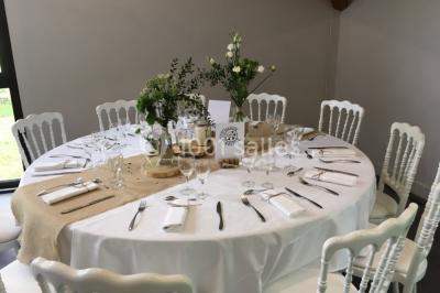 Salle de réunion lumineuse avec tables en U, chaises noires, grandes fenêtres donnant sur un jardin verdoyant.