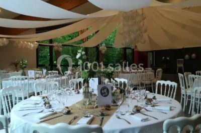 Salle de réunion lumineuse avec tables en U, chaises noires, grandes fenêtres donnant sur un jardin verdoyant.