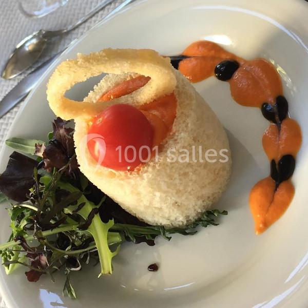 Assiette gastronomique avec un panier de pain garni de tomate cerise, sauce colorée et salade verte en accompagnement.