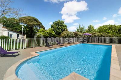 Salle de réunion lumineuse avec tables en U, chaises noires, grandes fenêtres donnant sur un jardin verdoyant.