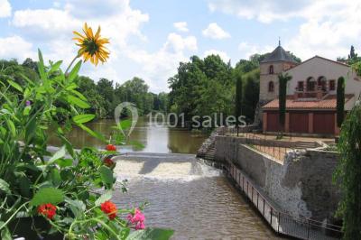 Salle de réunion lumineuse avec tables en U, chaises noires, grandes fenêtres donnant sur un jardin verdoyant.