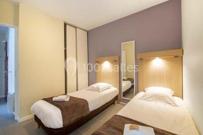 Salle de restaurant lumineuse avec tables dressées, bouteilles de vin, verres et décoration végétale.