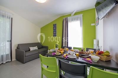Salle de restaurant lumineuse avec tables dressées, bouteilles de vin, verres et décoration végétale.