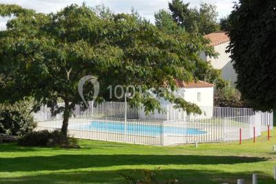 Salle de restaurant lumineuse avec tables dressées, bouteilles de vin, verres et décoration végétale.