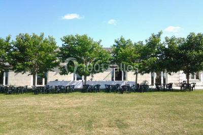 Chambre mansardée avec lit double, poutre apparente, télévision murale, commode, chaise et lampe de chevet.