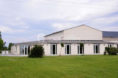 Chambre mansardée avec lit double, poutre apparente, télévision murale, commode, chaise et lampe de chevet.