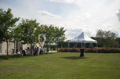 Chambre mansardée avec lit double, poutre apparente, télévision murale, commode, chaise et lampe de chevet.
