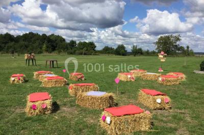 Chambre mansardée avec lit double, poutre apparente, télévision murale, commode, chaise et lampe de chevet.