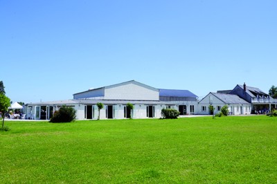 Chambre mansardée avec lit double, poutre apparente, télévision murale, commode, chaise et lampe de chevet.