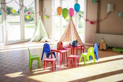 Chambre mansardée avec lit double, poutre apparente, télévision murale, commode, chaise et lampe de chevet.