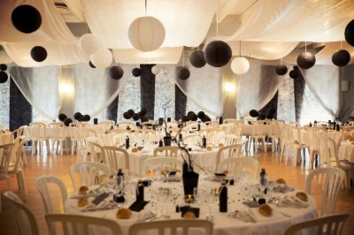 Chambre mansardée avec lit double, poutre apparente, télévision murale, commode, chaise et lampe de chevet.