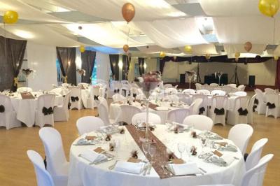 Chambre mansardée avec lit double, poutre apparente, télévision murale, commode, chaise et lampe de chevet.