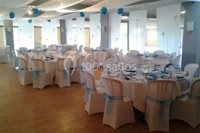 Chambre mansardée avec lit double, poutre apparente, télévision murale, commode, chaise et lampe de chevet.