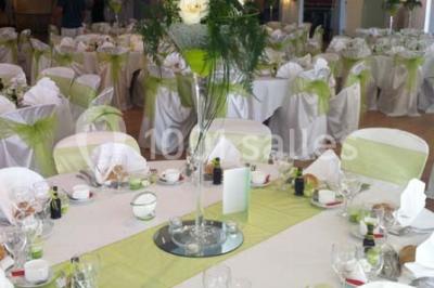 Chambre mansardée avec lit double, poutre apparente, télévision murale, commode, chaise et lampe de chevet.