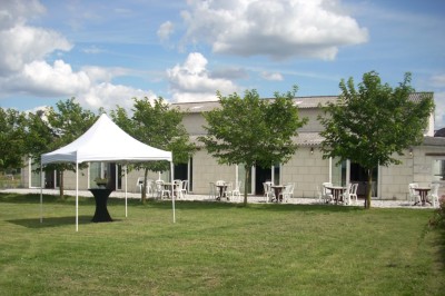 Chambre mansardée avec lit double, poutre apparente, télévision murale, commode, chaise et lampe de chevet.