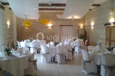 Chambre mansardée avec lit double, poutre apparente, télévision murale, commode, chaise et lampe de chevet.