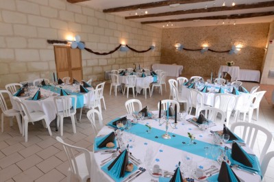 Chambre mansardée avec lit double, poutre apparente, télévision murale, commode, chaise et lampe de chevet.