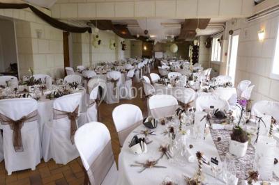 Chambre mansardée avec lit double, poutre apparente, télévision murale, commode, chaise et lampe de chevet.