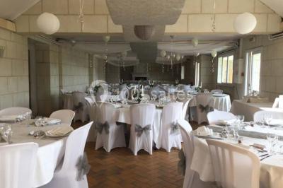 Chambre mansardée avec lit double, poutre apparente, télévision murale, commode, chaise et lampe de chevet.