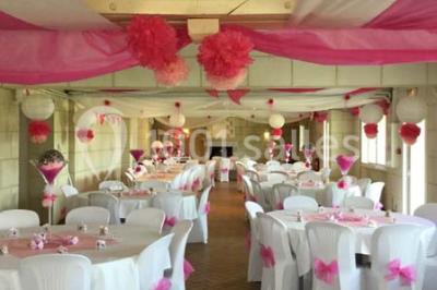 Chambre mansardée avec lit double, poutre apparente, télévision murale, commode, chaise et lampe de chevet.