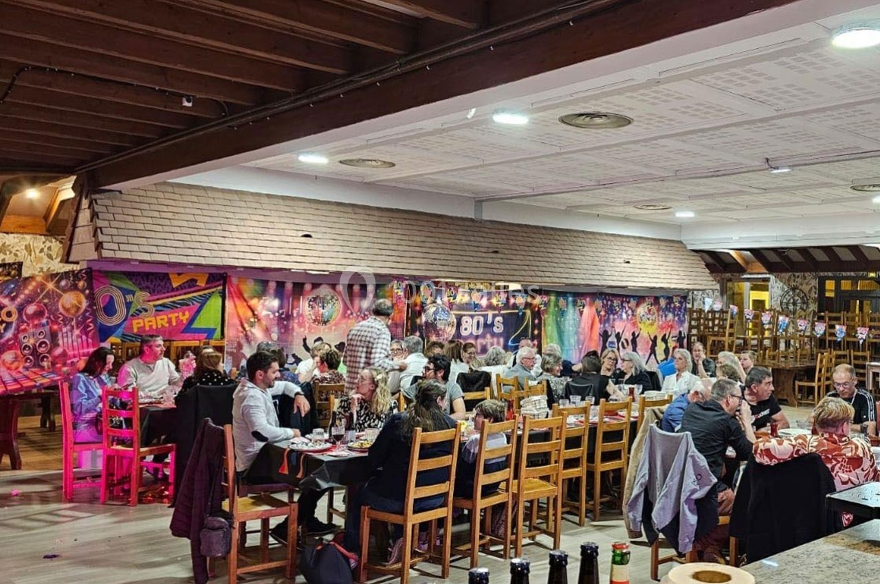 Salle décorée sur le thème des années 80 avec des convives assis à des tables lors d'un événement festif.