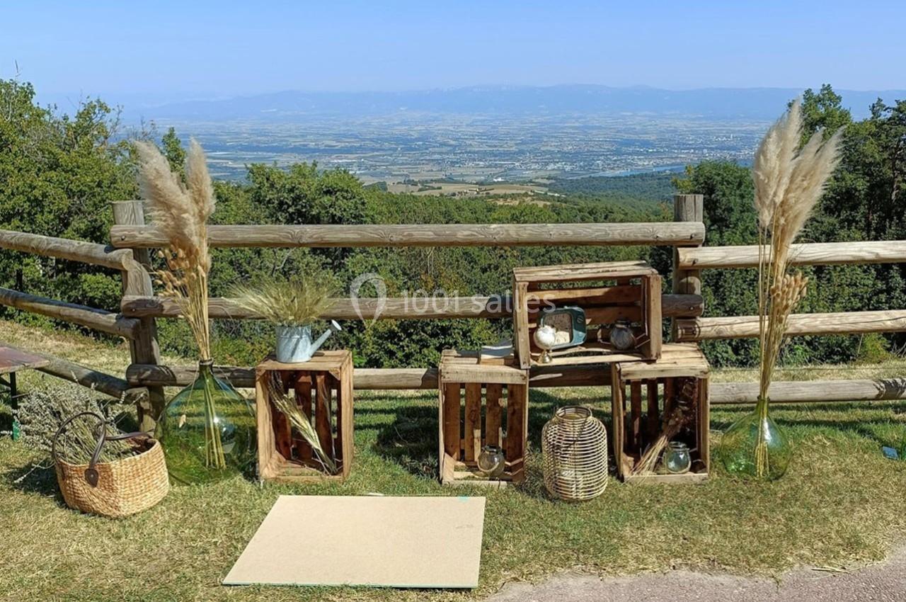 Décoration champêtre avec caisses en bois, vases de pampas et objets rustiques, sur fond de paysage vallonné.