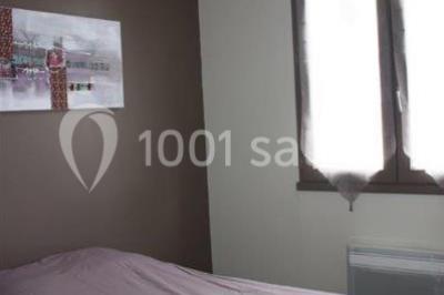 Deux lavabos blancs sur un meuble en bois avec miroirs, distributeur de savon mural et poubelle dans une salle de bain…