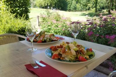Étang calme reflétant des arbres et une pelouse verdoyante avec un bunker de golf en arrière-plan.