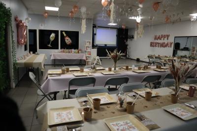 Salle décorée pour un événement avec des arches et colonnes de ballons beige et blanc, tables dressées avec vaisselle.