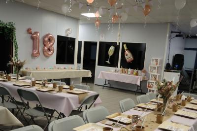 Salle décorée pour un événement avec des arches et colonnes de ballons beige et blanc, tables dressées avec vaisselle.
