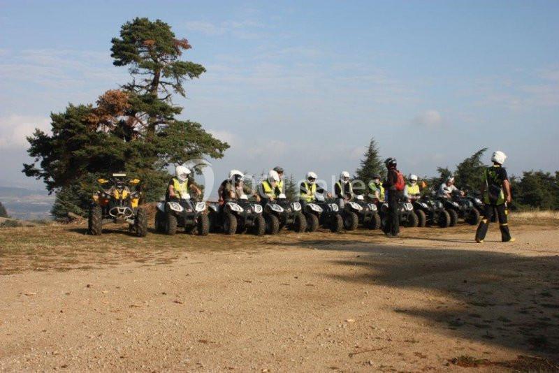 Groupe de personnes en tenue de protection alignées sur des quads dans un paysage naturel.