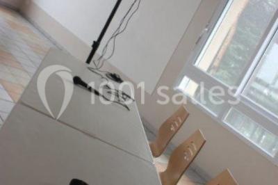 Bar lumineux blanc entouré de tabourets noirs et blancs dans une pièce avec vue sur une fenêtre en soirée.