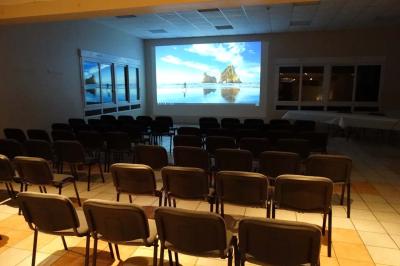Bar lumineux blanc entouré de tabourets noirs et blancs dans une pièce avec vue sur une fenêtre en soirée.
