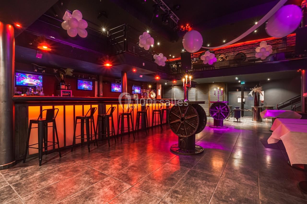 Salle de bar décorée avec des lumières rouges, des ballons blancs et un comptoir avec des tabourets hauts.