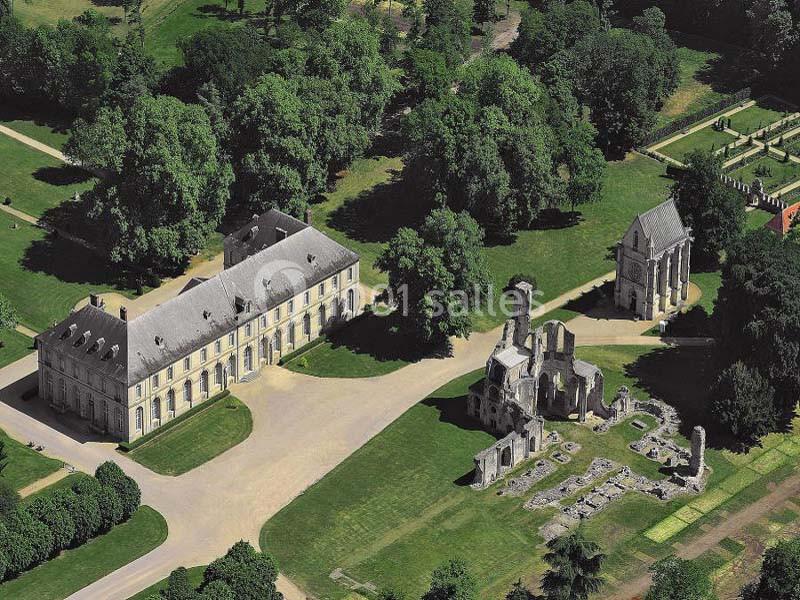 Vue aérienne d'un domaine avec un bâtiment historique, des ruines et un parc arboré.