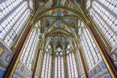 Intérieur d'une chapelle gothique avec des vitraux colorés, des voûtes ornées et des peintures murales détaillées.