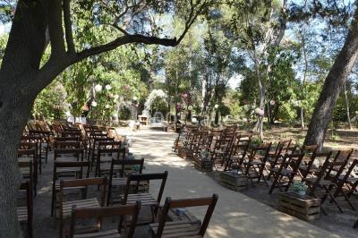 Tente en toile beige installée sur un sol gravillonné, entourée d'arbres, avec des lits aménagés à l'intérieur.