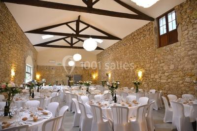 Tente en toile beige installée sur un sol gravillonné, entourée d'arbres, avec des lits aménagés à l'intérieur.