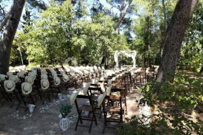 Tente en toile beige installée sur un sol gravillonné, entourée d'arbres, avec des lits aménagés à l'intérieur.